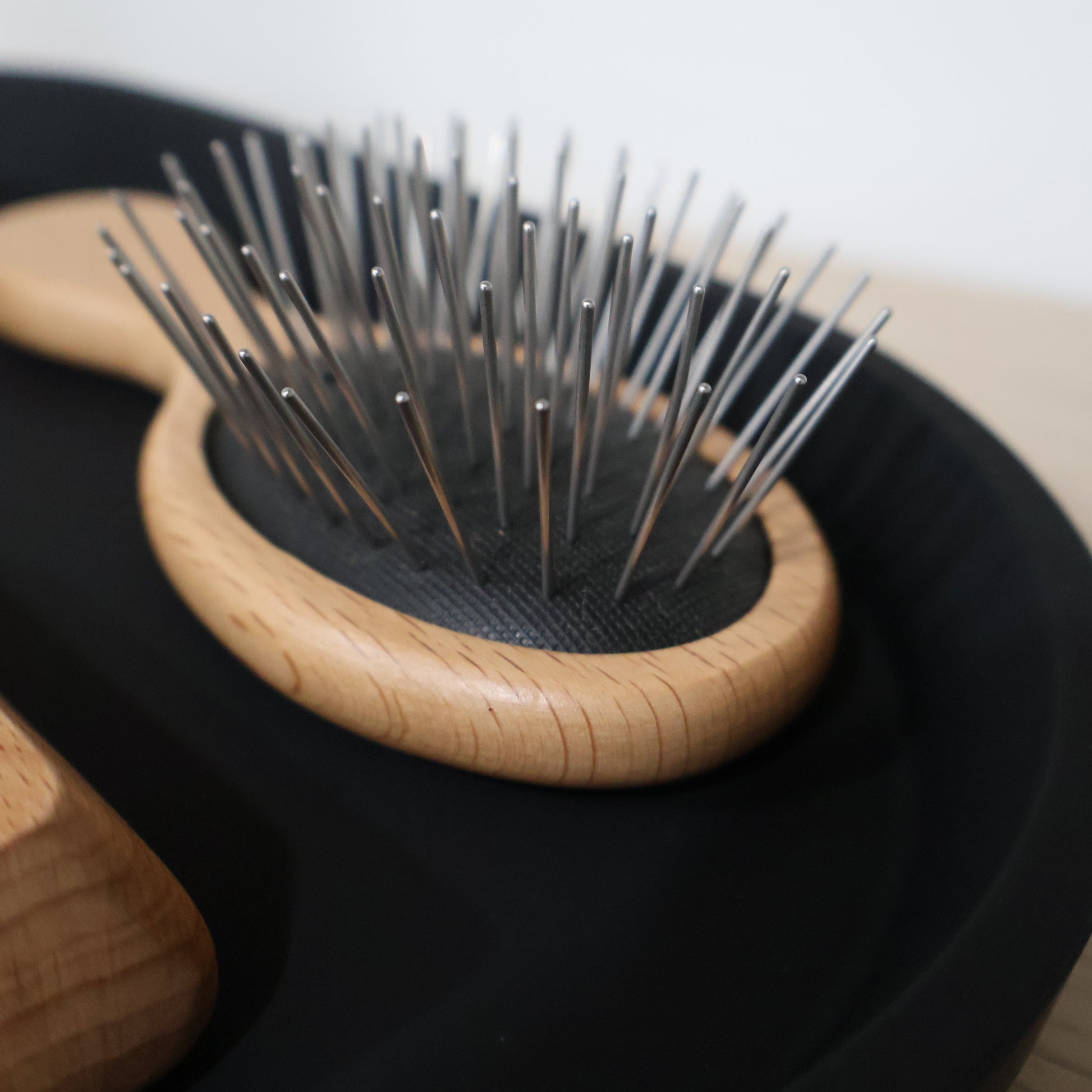 Small wooden hairbrush with metal bristles on a black background